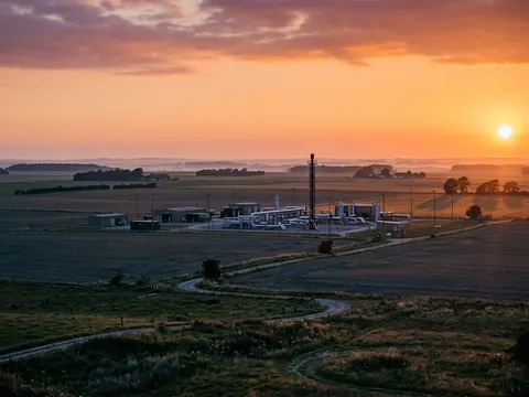 Les installations de surface d'un stockage souterrain de gaz au milieu de prairies plates, sous un ciel orange de fin de journée.